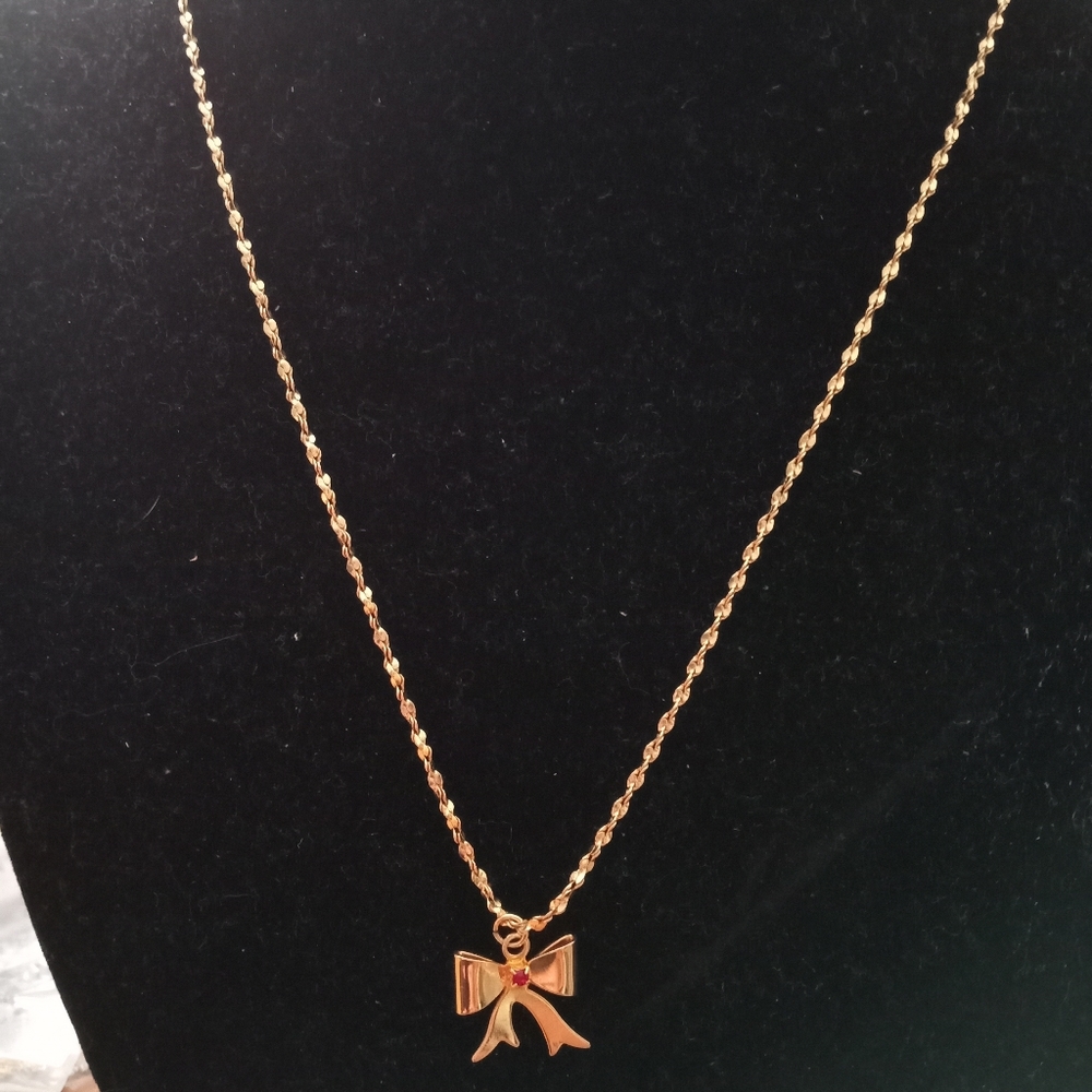 Gold now necklace with ruby jewel